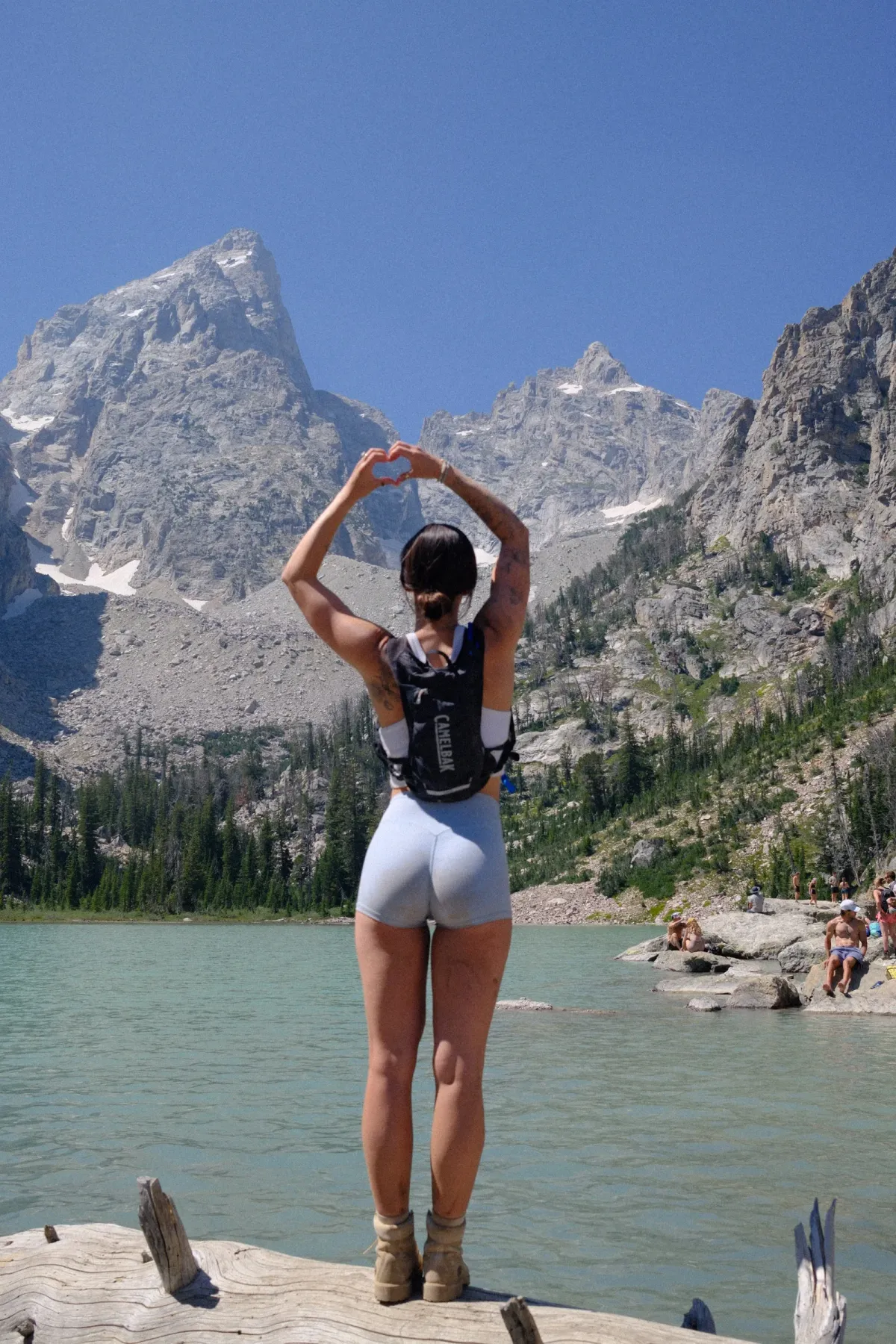 Emma making a heart with her hands at an alpine lake below the Tetons