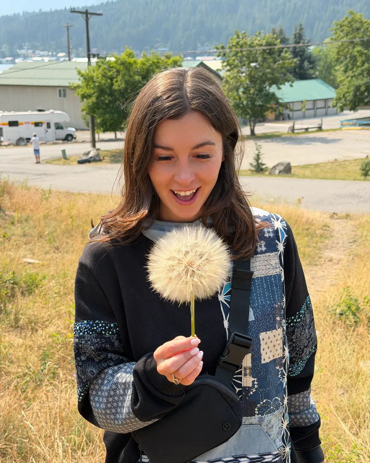 Emma laughing at a giant dandelion clock she’s just picked
