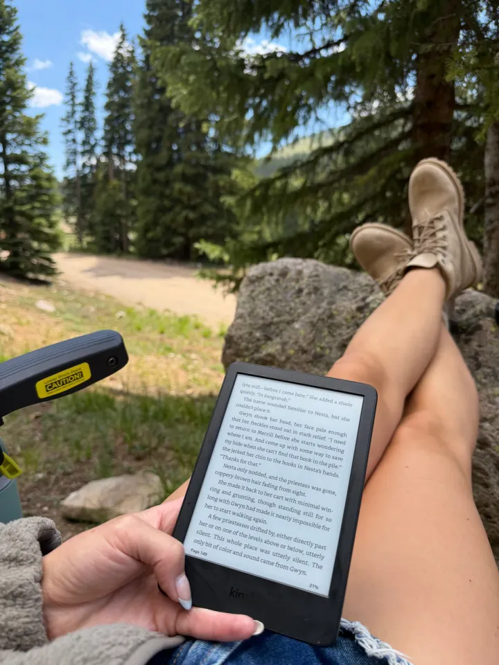 Reading a Kindle in a camp chair, boots up on a rock