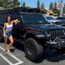 Emma Sinclair beside her black Jeep Gladiator with rooftop tent